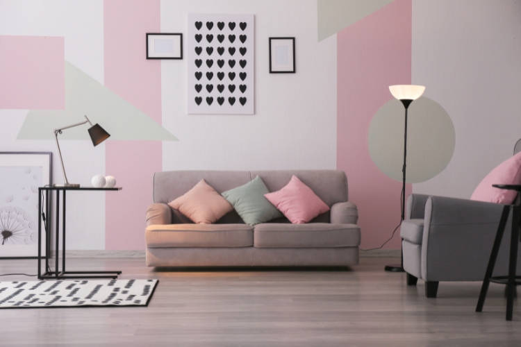 Nappali falain pasztell rózsaszín, bézs és halványzöld dekoratív falfestés geometrikus mintákkal, amelyek lágy, harmonikus vizuális hatást és modern színrétegezést mutatnak.